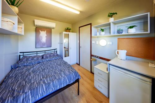 a bedroom with a bed and a dresser and shelves at KUR-Cow farm escape 35 minutes from Cairns in Kuranda