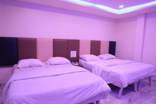 2 camas en una habitación con paredes rosas y blancas en KAPILA RESIDENCY, en Bangalore