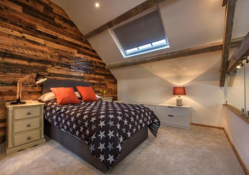 1 dormitorio con pared de ladrillo y 1 cama con almohadas de color naranja en Ty Nain en Pwllheli