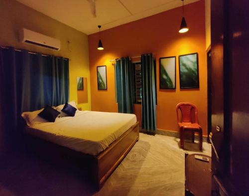 a bedroom with a bed and a red chair at Housefull Residency in Khandagiri
