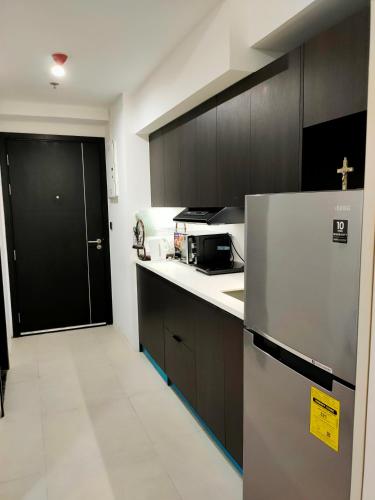 a kitchen with a stainless steel refrigerator and black cabinets at Aeon Towers studio unit in Davao City
