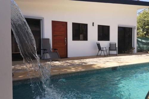 a swimming pool with a fountain in front of a house at Casa Mar de Sueños Tamarindo in Tamarindo