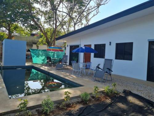 a house with a pool and chairs and an umbrella at Casa Mar de Sueños Tamarindo in Tamarindo