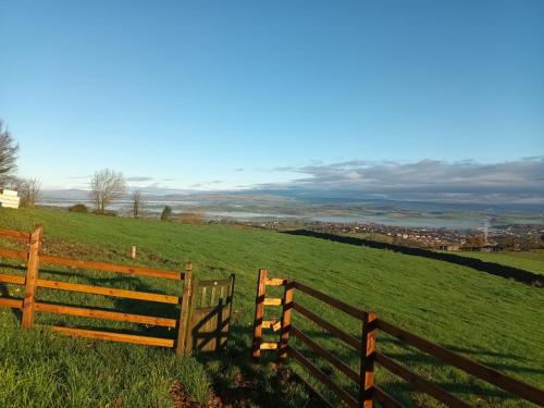 a wooden fence on a green field with a view at The Herdsman Luxury Shepherds Hut in Barnoldswick