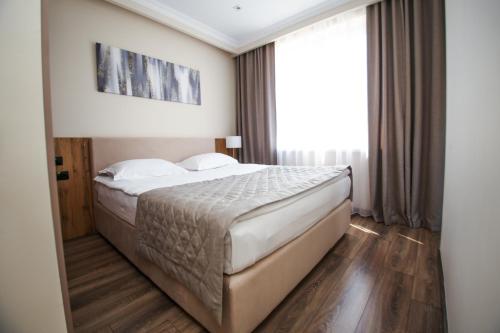 a bedroom with a bed and a large window at Chagala Residence Atyrau in Atyraū