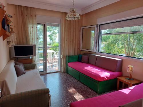 a living room with a couch and a tv at ALKIONIS , Family apartment by the sea in Halkidiki in Pefkohori