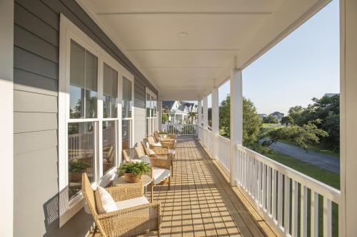 un porche con sillas y mesas en una casa en Harkers Hideaway home, en Harkers Island