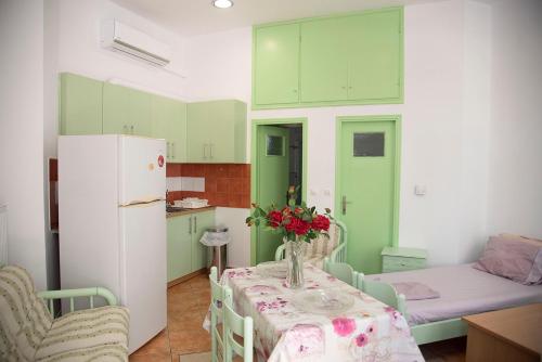 a kitchen with green cabinets and a table with flowers on it at STAVROS Studio Apartment in kos town in Kos