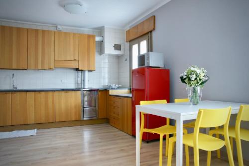 a kitchen with a table and yellow chairs and a red refrigerator at B&B The Secret Garden in Buia