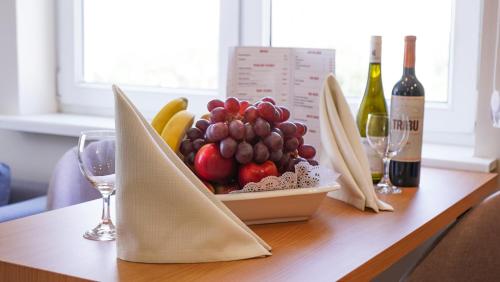 a bowl of fruit on a table with wine glasses at Chagala Residence Atyrau in Atyraū