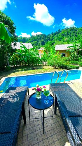 a table with flowers on it next to a pool at Peaceful Retreat Villa by Nai Thon beach in Phuket