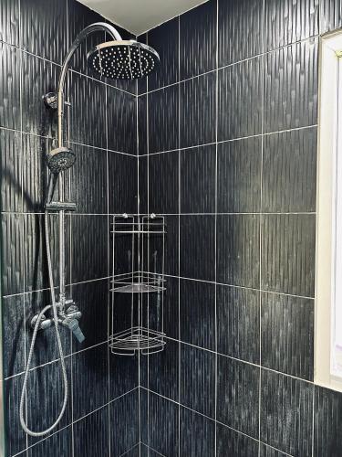 a black tiled bathroom with a shower with two baskets at Peaceful Retreat Villa by Nai Thon beach in Phuket