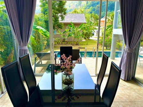 a glass table with a vase of flowers on it at Peaceful Retreat Villa by Nai Thon beach in Phuket