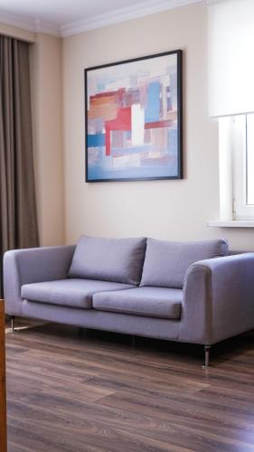 a blue couch in a living room with a painting at Chagala Residence Atyrau in Atyraū