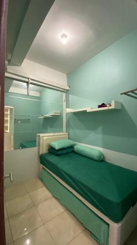 a small room with a green bed and shelves at Apartemen Panoramic by Dio Property in Bandung