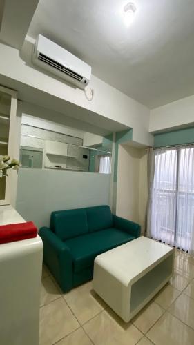 a living room with a blue couch and a air conditioner at Apartemen Panoramic by Dio Property in Bandung