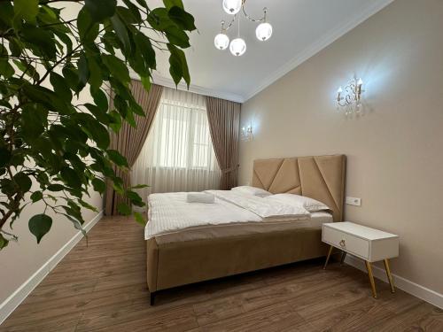 ein Schlafzimmer mit einem Bett und einer Topfpflanze in der Unterkunft Home Apartment Luxe in Schymkent