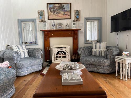a living room with a table and chairs and a fireplace at Cherry Blossom Cottage-with country charm and spa in Stanthorpe