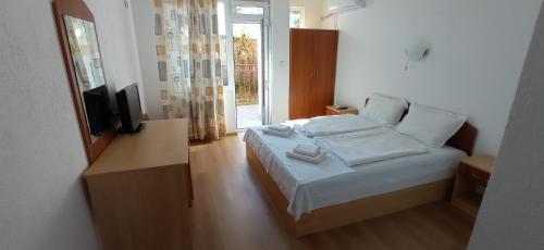 a bedroom with a bed with a television and a window at Хотел Милев in Kiten