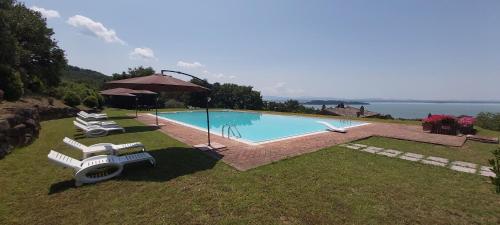 uma piscina com duas espreguiçadeiras e um guarda-sol em Casale sul Lago Trasimeno em San Feliciano