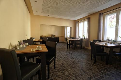 a dining room with tables and chairs and windows at Pension Am Park in Bad Muskau