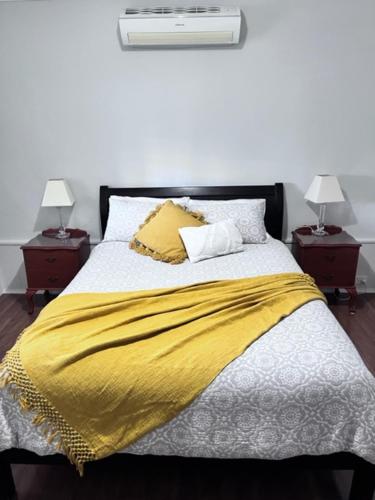 a bed with a yellow blanket and two night stands at Penzance Cottage in Adelaide