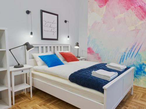 1 dormitorio con cama blanca y pared colorida en OK KRAK Apartments, en Cracovia