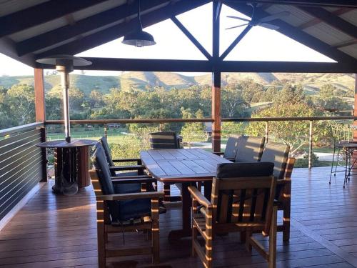 a wooden table and chairs on a deck with a view at Strath Creek Station farm-stay in Strath Creek