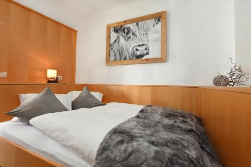 a bedroom with a white bed with a picture on the wall at Hotel Die Montafonerin in Vandans