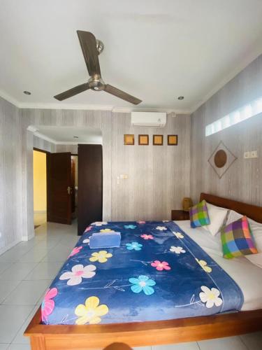a bed with a blue blanket with flowers on it at Nami House in Ubud