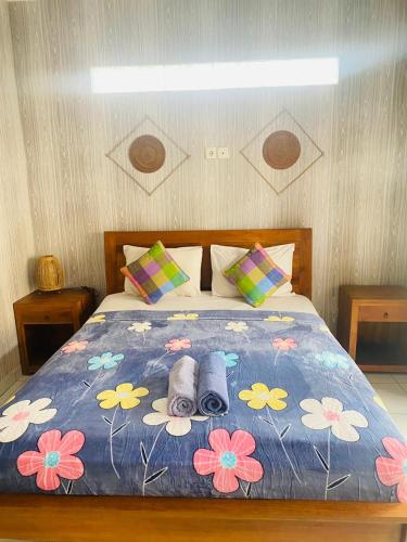 a bed with a blue blanket with flowers on it at Nami House in Ubud