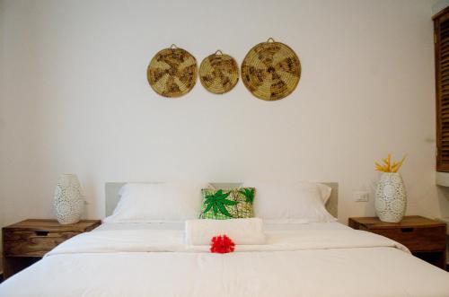 a bedroom with a white bed with three plates on the wall at CDM Villas Kiwengwa in Kiwengwa