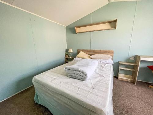 1 dormitorio con 1 cama con sábanas y almohadas blancas en Lovely 6 Berth Caravan With Decking, Close To The Beach In Suffolk Ref 68075bs en Lowestoft