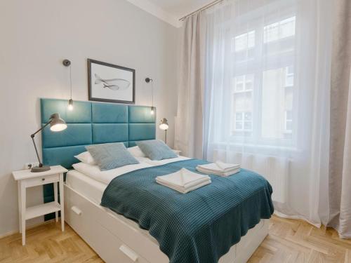 1 dormitorio con 1 cama con cabecero azul y ventana en OK KRAK Apartments, en Cracovia