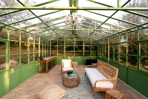 a green greenhouse with a couch and chairs in it at Al Piglio Maison de Charme Wine & Wellness Resort in Piglio