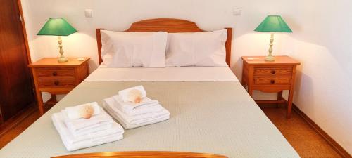 una camera da letto con un letto con due asciugamani e due lampade di Albufeira Apart AE - Sea & Old Town View ad Albufeira