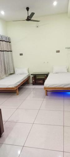two beds in a room with white tile floors at Shaury Homestay in Garudeshwar