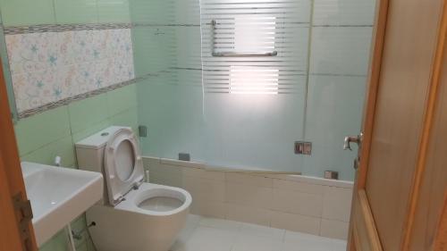 a white bathroom with a toilet and a sink at Baran Homestay in Muscat
