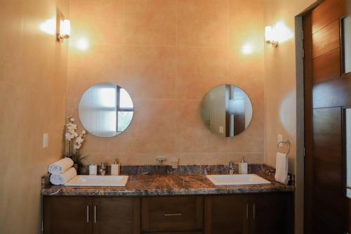 a bathroom with two sinks and two mirrors at Super casa, la mejor vista de Huatulco in Tangolunda