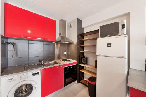 een keuken met rode kasten en een wasmachine bij Aka Appart'Hotel " Le Petit Coin de Lavaur" in Lavaur