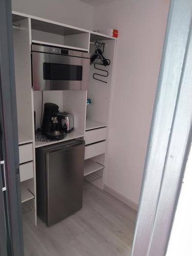 une cuisine avec une cuisinière et un micro-ondes dans l'établissement CHARMANT STUDIO VILLAGE NATURISTE CAP AGDE, au Cap d'Agde