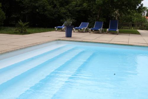 una piscina con sillas azules y una mesa en Gite de la Laiterie en Bouaye