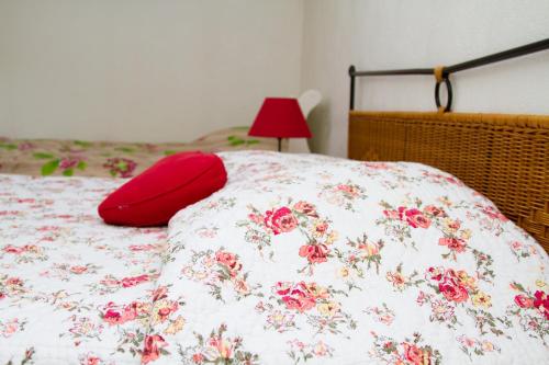 uma cama com um cobertor floral com uma almofada vermelha em Gite de la Laiterie em Bouaye