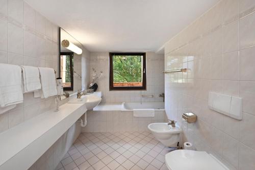 a bathroom with two sinks and a toilet and a tub at Hotel Die Montafonerin in Vandans