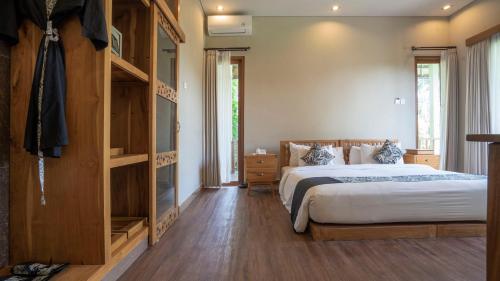 a bedroom with a large bed and wooden floors at KajaNe Mua at Ubud Bali in Ubud