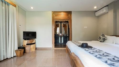 a bedroom with a large bed and a television at KajaNe Mua at Ubud Bali in Ubud