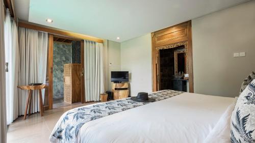 a bedroom with a large bed and a television at KajaNe Mua at Ubud Bali in Ubud