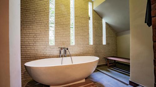 a bath tub in a bathroom with a brick wall at KajaNe Mua at Ubud Bali in Ubud
