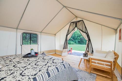 a tent with a bed and a chair in a room at Experience Nature Glamping - Roaring River in Cassville