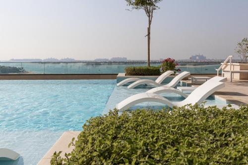 uma piscina com duas cadeiras brancas na água em Privet Beach with stunning Sea view em Dubai